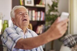 homem com presbiopia ou síndrome do braço curto afastando o celular dos olhos